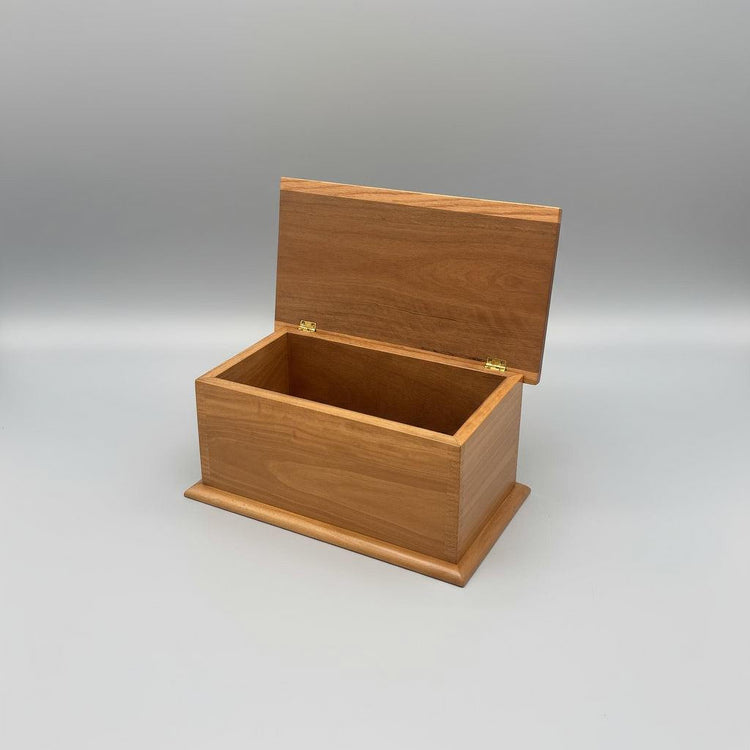 A handcrafted wooden keepsake box made of Spotted Gum timber, with a lid open, placed on a wooden floor.