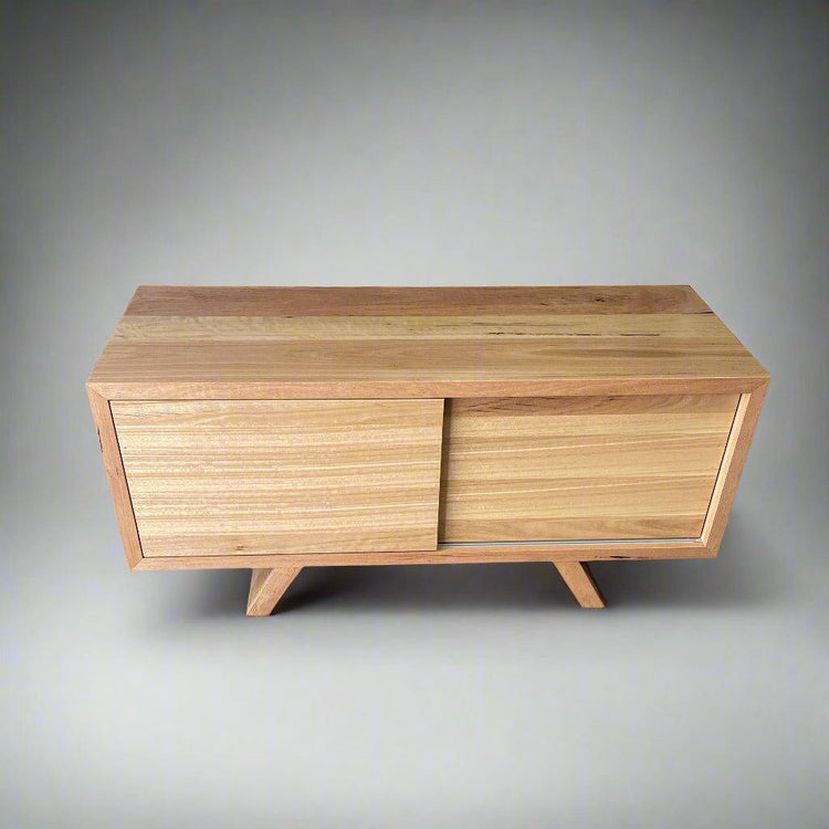 A custom-made wooden entertainment unit with sliding doors and splayed legs, crafted from Australian hardwood.