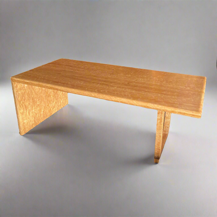 A modern one-edged waterfall coffee table made of Birdseye Blackbutt timber with mitred edges, displayed in a showroom setting.