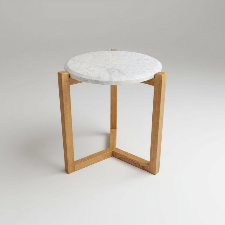 Small round table with marble top and wooden frame on a light gray background
